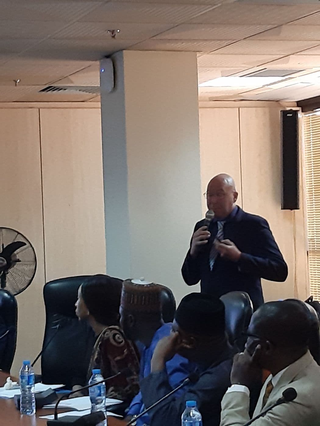 Presenter speaking into a microphone to seated delegates