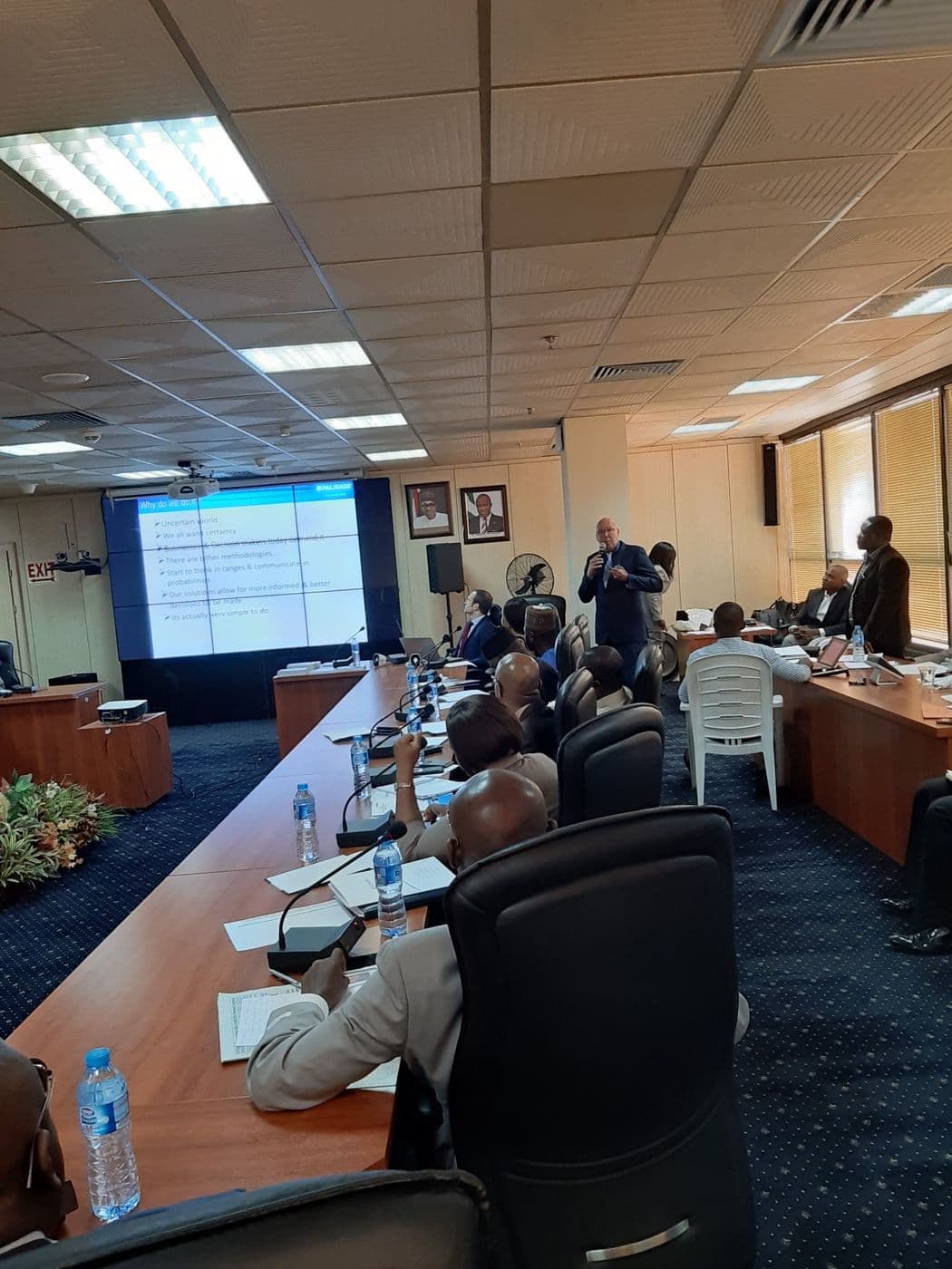 Delegates along the conference table, with the presentation screen at the far end
